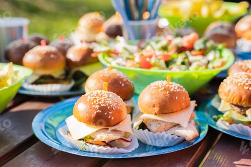Preview: Buffet table with many mini burgers at outdoors birthday party for children, kids. Catering at weddi