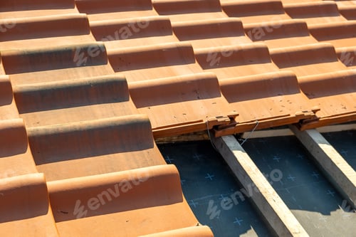 Preview: Overlapping rows of yellow ceramic roofing tiles mounted on wooden boards covering residential
