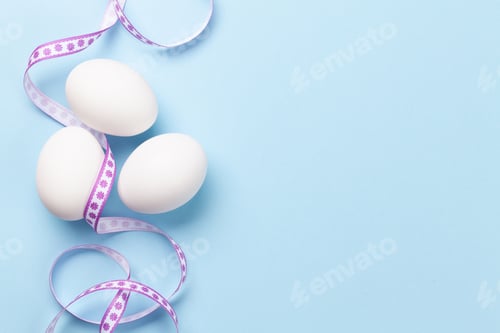White Eggs Decorated with Purple Ribbon on Blue