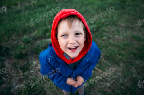 Preview: Smiling Child Poses Outdoors in Red Hood