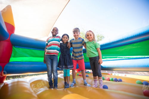 Preview: Portrait of friends with arms around standing on bouncy castle