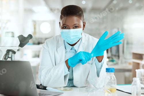 Preview: Shot of a young scientist sitting alone in her laboratory and putting surgical gloves on