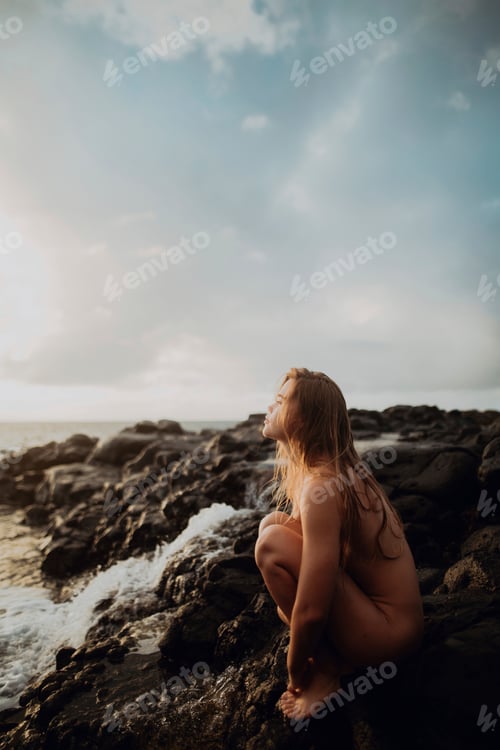 Preview: Naked woman sitting on rocks by sea, Princeville, Hawaii, US