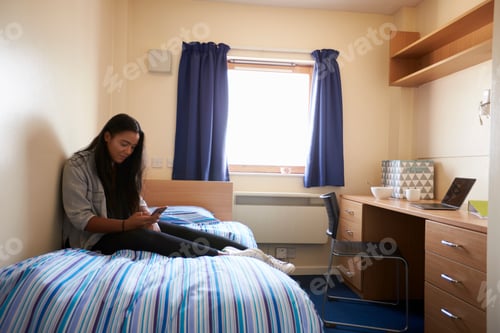 Preview: Student Uses Mobile Phone In Bedroom Of Campus Accommodation
