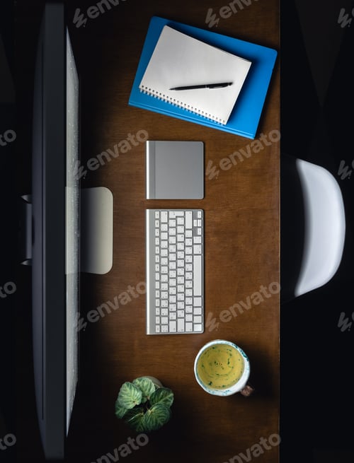 Preview: Computer, notepads and a cup of tea on the desktop at night, top view.