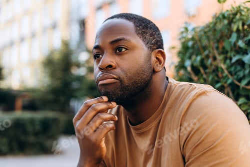 Preview: Portrait of young African American man sitting in the city thinking