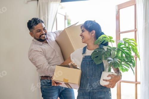 Preview: Couple indian happy carrying box on moving day in of home new