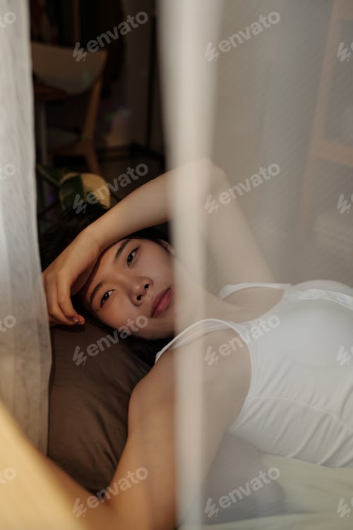 Preview: Woman with hangover resting on bed