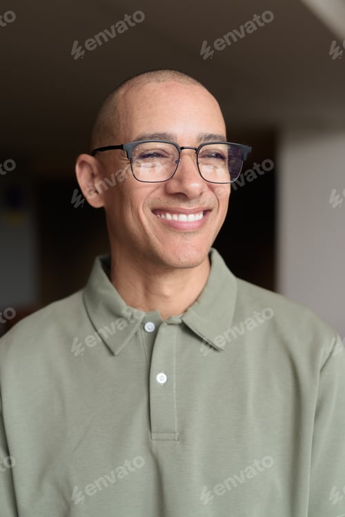 Preview: Bald Hispanic man in hotel lobby with eyeglasses, stylish confident portrait in casual setting