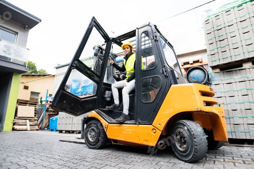 Preview: Female forklift truck driver outside a warehouse.