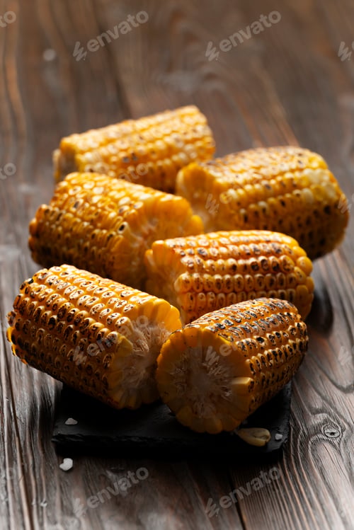 Preview: Slate tray with Pieces of Grilled corn on the cob on kitchen table healthy food background