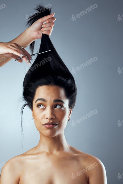 Preview: Time for the big cut. Studio shot of young woman getting her hair cut against a grey background.