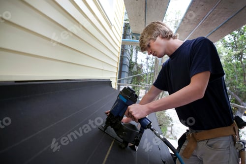 Preview: Teenage boy using nail gun on construction site