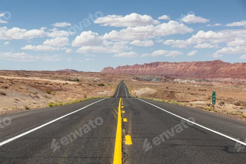 Preview: Scenic Road in the Dry Desert with Red Rocky Mountains in Background.