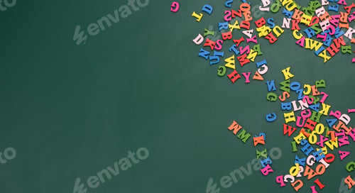 Preview: Multicolored wooden letters of the english alphabet on a green background, top view