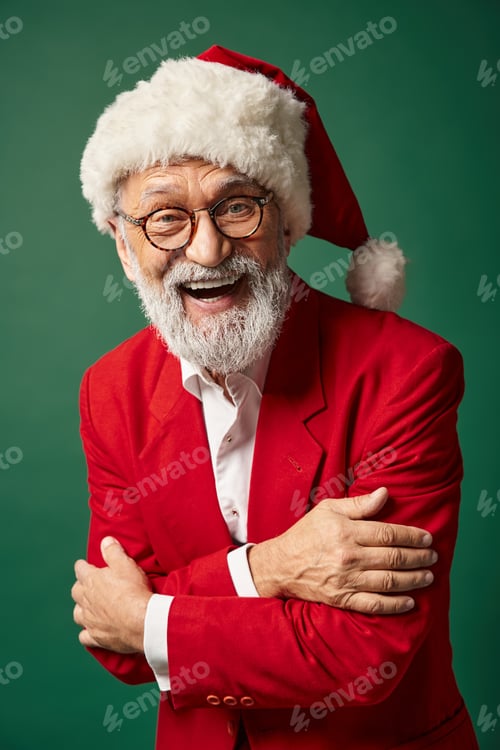 Preview: cheerful man dressed as Santa posing on green backdrop and smiling at camera, winter concept