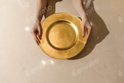 Preview: Golden metal plate in female hands on light table