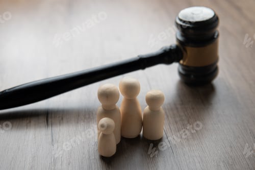 Preview: A gavel and four wooden figurines representing a family on a table.