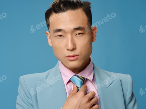 Preview: businessman in a classic suit straightens a tie around his neck on a blue background cropped view