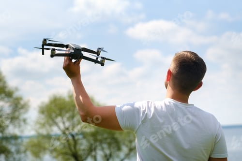 Preview: A man with a flying vehicle in his hands, raised to the sky in nature.Launching a drone