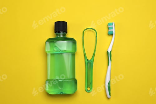 Preview: Tongue cleaner, mouthwash and toothbrush on yellow background, flat lay