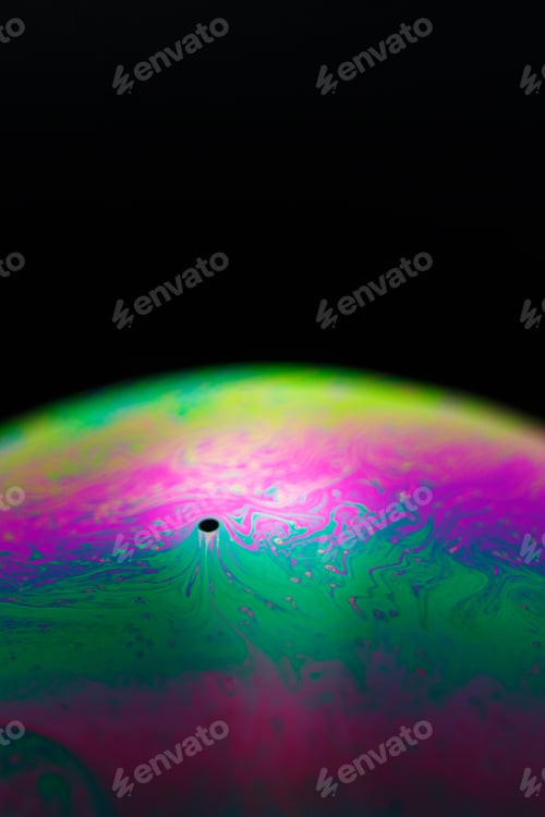 Preview: Rainbow soap bubble on a black background. Close-up of a colorful surface.