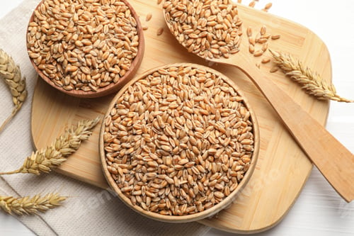 Preview: Wheat grains in bowls and spoon on wooden board, flat lay
