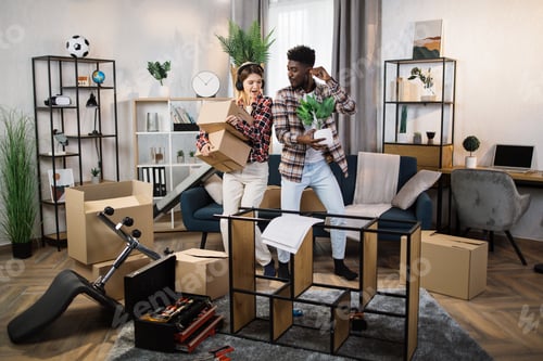 Preview: Multiracial couple dancing at living room with boxes around