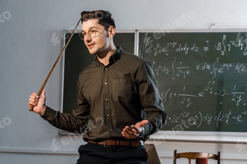 Preview: handsome male teacher in formal wear holding wooden pointer and explaining equations in class
