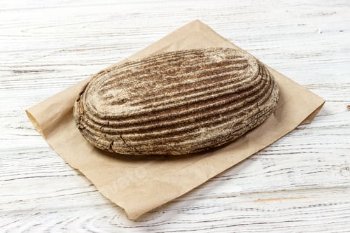 Preview: Loafs of rye bread on wood background with paper bag. Top view