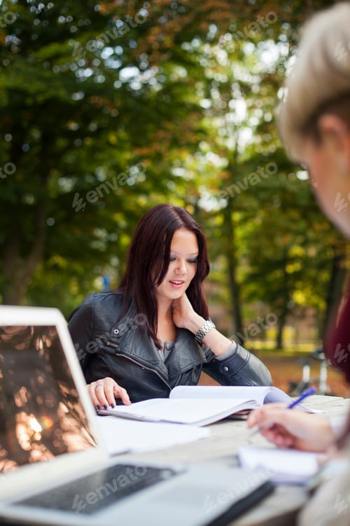 Preview: Young female friends studying at table in campus