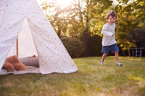 Preview: Young Boy Running And Having Fun With Tent Or Tepee Pitched In Garden