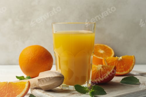 Preview: Board with glass of orange juice, oranges and juicer on wooden background