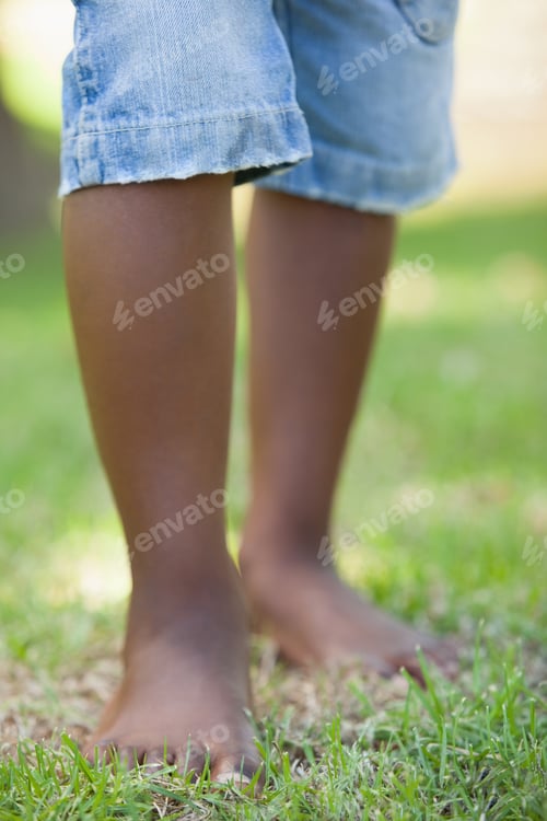Preview: Little boys legs standing on grass on a sunny day