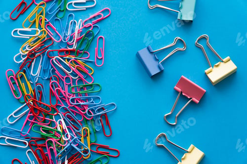 Preview: top view of colorful paper clips and fold back clips on blue