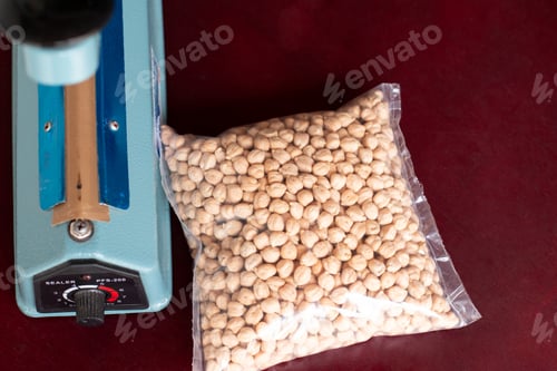 Preview: Bag of chickpeas sealed next to the sealer. Plastic film sealer. Concept of manual and simple works.
