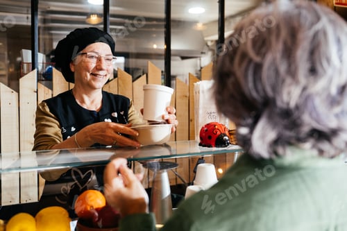 Preview: Smiling Woman Serving Takeaway Meal to Customer at Food Shop Counter