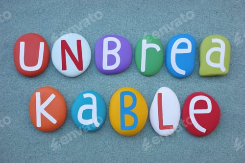 Preview: Unbreakable, creative text composed with multi colored stone letters over green sand