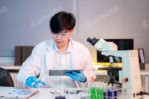 Preview: Asian man scientist researcher holding tablet looking at plant test sample at work table in lab room