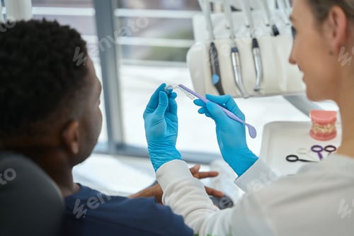 Preview: Woman dentist showing which tooth will be straighten wearing aligners
