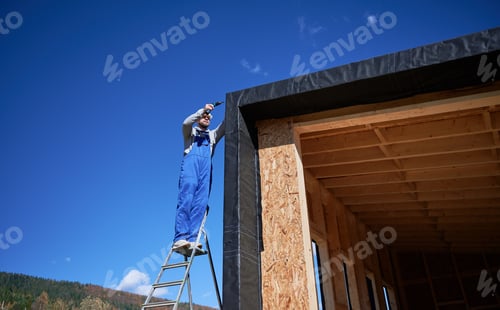 Preview: Builder installing corrugated iron sheet used as facade of future wooden frame house.