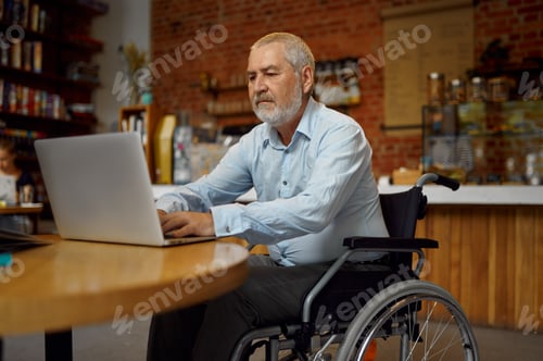 Preview: Adult disabled man in wheelchair using laptop