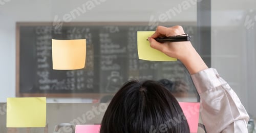 Preview: Close up hand businesswoman writing sticky notes on glass wall in office