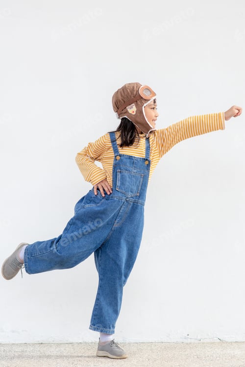 Preview: A cute little girl dressed in a cap and glasses of a pilot. The child dreams of becoming a pilot.