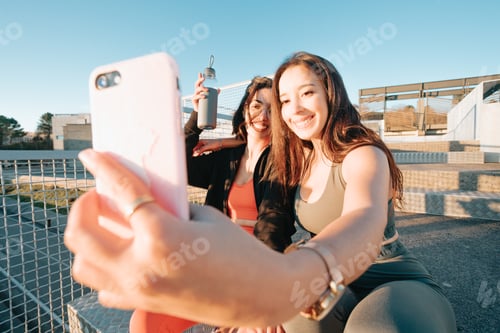 Preview: Two young sporty woman friends taking selfies with smart phone between exercises