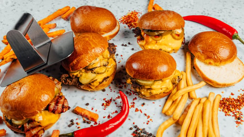 Preview: Closeup shot of tasty smash burgers, French fries, and red spicy pepper on the white background