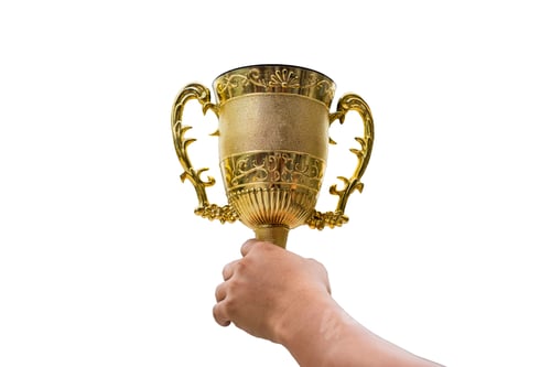 Preview: Hand holding golden trophy cup raise up on background