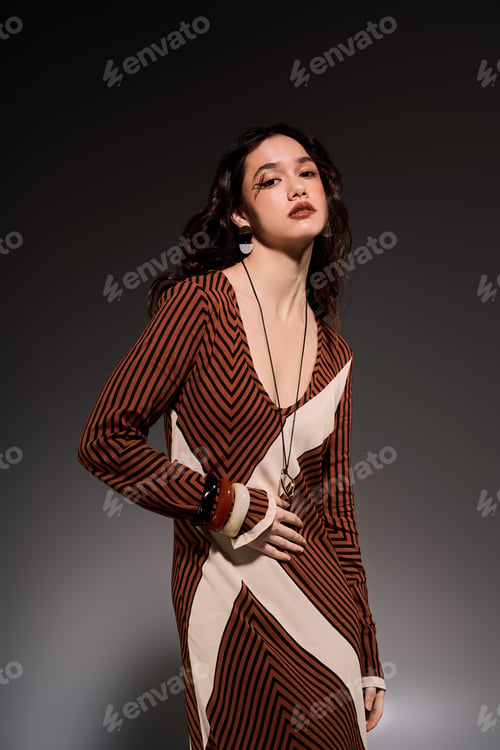 Preview: Stylish young woman poses gracefully in a striped dress within a modern studio setting