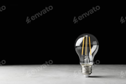 Preview: Vintage lamp bulb on light table against black background. Space for text