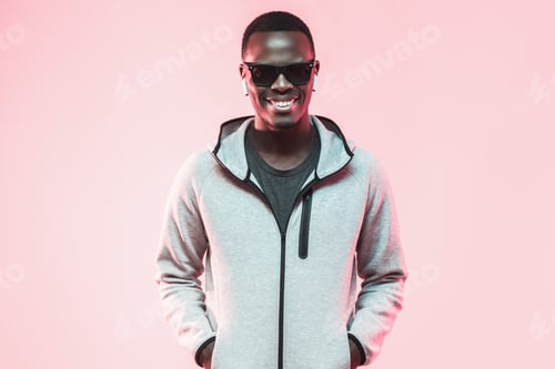 Preview: Handsome african american guy in gray hoodie standing isolated on pink background